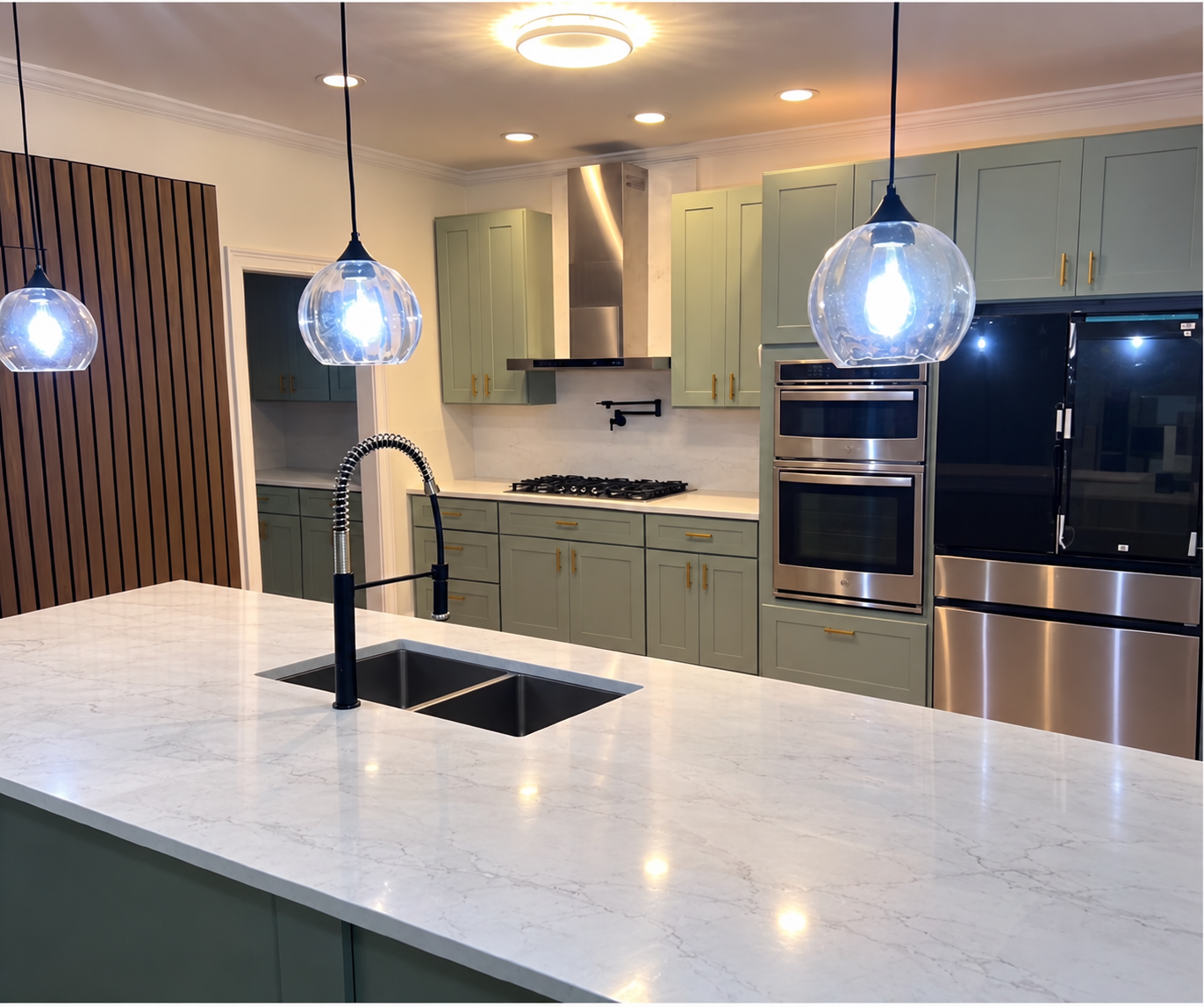 Finished modern kitchen with green cabinetry, bright countertops and pendant lighting
